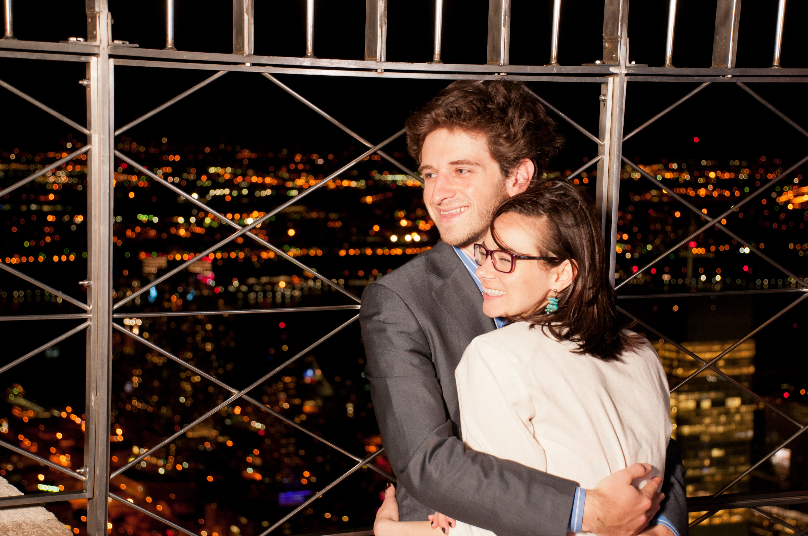 People looking out at NYC from the 86th floor observation deck at the Empire State Building Observatory.