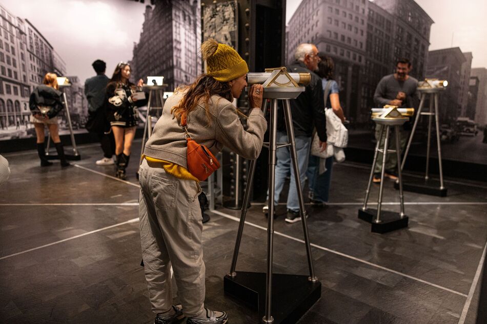 Woman looking in a telescope at the second floor museum experience at the Empire State Building Observatory