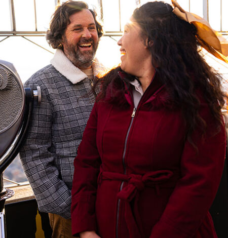 People looking out at NYC from the 86th floor observation deck at the Empire State Building Observatory.